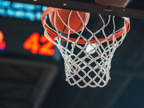 Basketballkorb mit Ball, der im Netz steckt, im Vordergrund; im Hintergrund ist die Punktzahl 42 zu sehen.